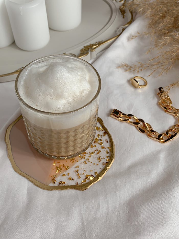 A stylish coffee presentation with gold jewelry on a white background.